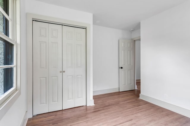 unfurnished bedroom featuring wood finished floors, a closet, and baseboards