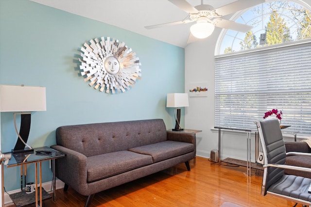 living area featuring wood finished floors, a ceiling fan, baseboards, and lofted ceiling