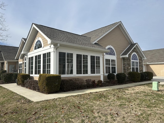 view of property exterior with a shingled roof and a yard