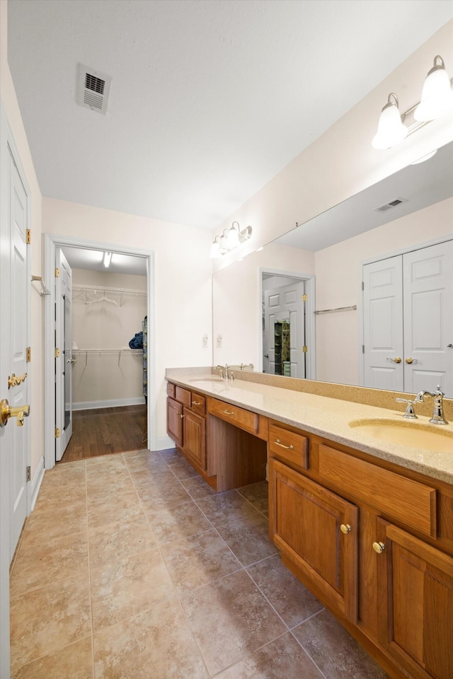 bathroom featuring double vanity, a walk in closet, tile patterned flooring, and baseboards