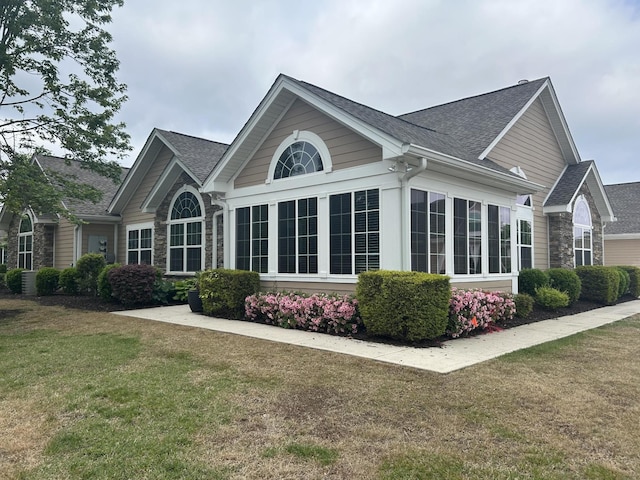 view of property exterior with a yard, a shingled roof, and stone siding