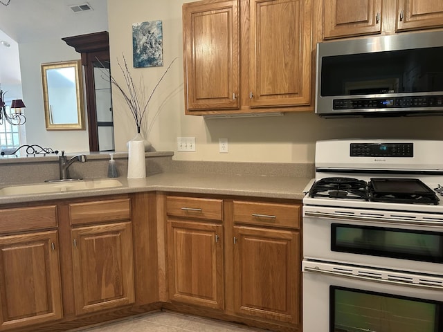 kitchen featuring stainless steel microwave, double oven range, a sink, and brown cabinets