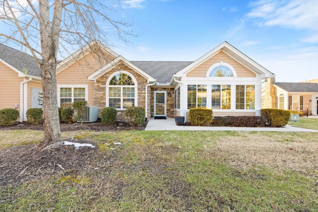 rear view of property featuring stone siding, central AC, and a lawn