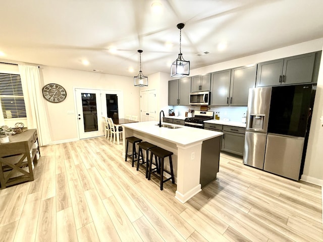 4524 Hoboken Way, Murfreesboro, TN 37128 - kitchen with appliances with stainless steel finishes, a sink, gray cabinetry, a kitchen breakfast bar, and light wood-style flooring