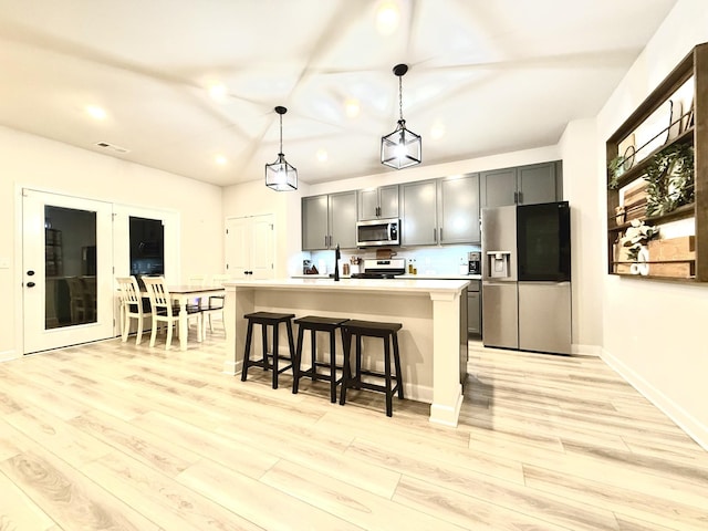4524 Hoboken Way, Murfreesboro, TN 37128 - kitchen featuring appliances with stainless steel finishes, light wood-style floors, a kitchen bar, light countertops, and hanging light fixtures