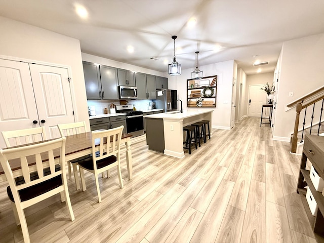 4524 Hoboken Way, Murfreesboro, TN 37128 - kitchen featuring appliances with stainless steel finishes, light countertops, a kitchen breakfast bar, a sink, and light wood-type flooring