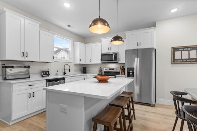178 Charleston Ave, Pleasant View, TN 37146 - kitchen with stainless steel appliances, a sink, a breakfast bar area, white cabinetry, and a kitchen island
