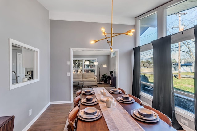 dining space with a chandelier, plenty of natural light, a high ceiling, wood finished floors, and baseboards