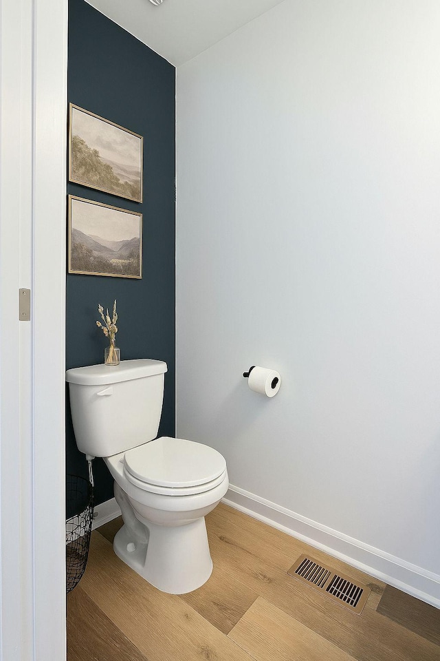 bathroom with baseboards, wood finished floors, and toilet