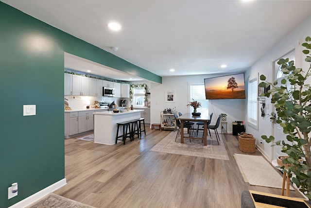 dining room with recessed lighting, baseboards, and light wood-style flooring
