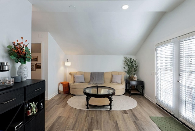 living room featuring lofted ceiling, light wood finished floors, and baseboards