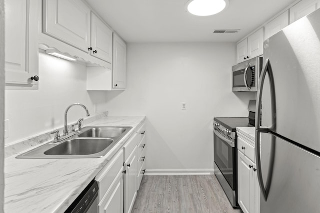1129 W Main St Unit 21, Franklin, TN 37064 - kitchen featuring stainless steel appliances, a sink, white cabinets, light wood-style floors, and baseboards