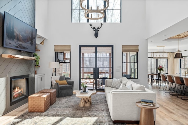 7361 Liberty Rd, Fairview, TN 37062 - living room featuring a glass covered fireplace, wood finished floors, french doors, a chandelier, and a high ceiling