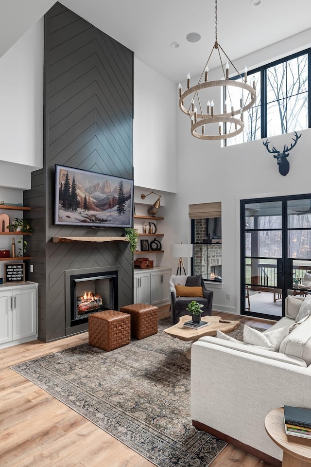 7361 Liberty Rd, Fairview, TN 37062 - living room featuring a fireplace, a high ceiling, wood finished floors, french doors, and a chandelier