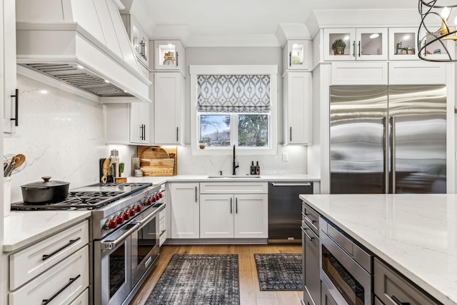 5012 Toll Road Ct, Thompsons Station, TN 37179 - kitchen with custom exhaust hood, built in appliances, a sink, light wood finished floors, and decorative backsplash