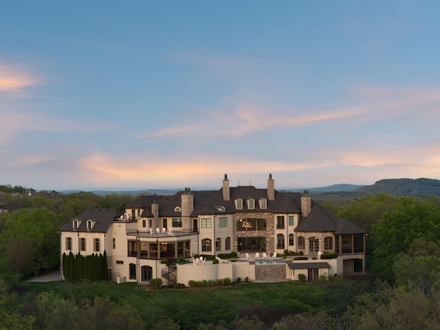 513 King Richards Ct, Franklin, TN 37067 - back of property at dusk with a balcony, stucco siding, a chimney, a patio, and a mountain view