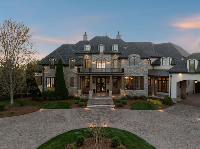 513 King Richards Ct, Franklin, TN 37067 - french country home featuring stone siding, a balcony, a chimney, curved driveway, and french doors