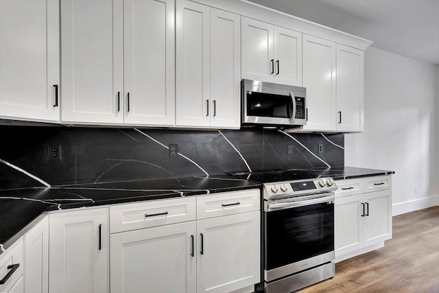 7592 Grasshopper Rd, Georgetown, TN 37336 - kitchen with appliances with stainless steel finishes, backsplash, light wood-type flooring, white cabinets, and dark countertops
