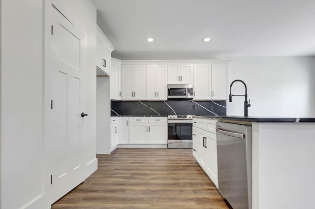 7592 Grasshopper Rd, Georgetown, TN 37336 - kitchen with stainless steel appliances, dark countertops, recessed lighting, decorative backsplash, and white cabinetry