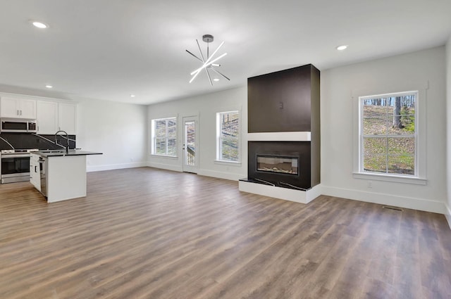 7592 Grasshopper Rd, Georgetown, TN 37336 - unfurnished living room featuring baseboards, dark wood finished floors, a large fireplace, recessed lighting, and a chandelier
