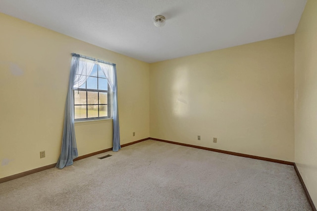 spare room featuring light colored carpet and baseboards
