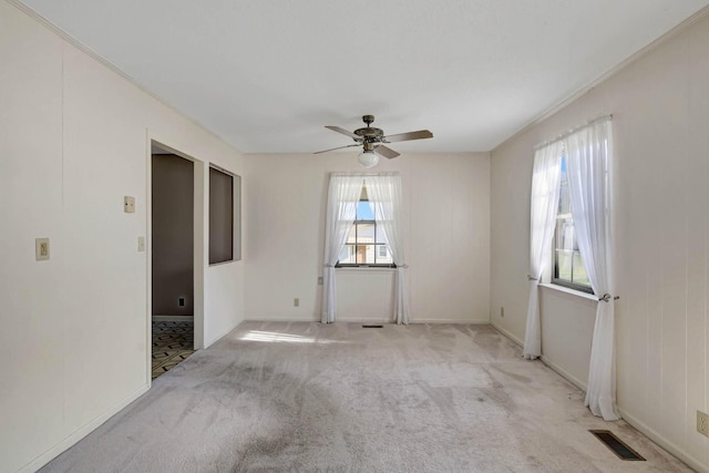 carpeted empty room with a ceiling fan and baseboards