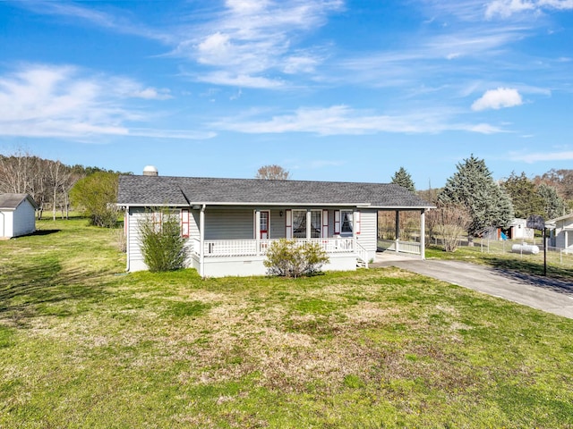 ranch-style home featuring covered porch, a front yard, driveway, a chimney, and an outdoor structure
