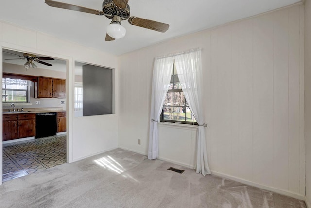 unfurnished dining area featuring ceiling fan, a sink, light colored carpet, and baseboards