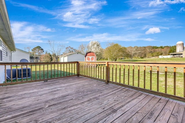 wooden terrace with a storage unit, an outbuilding, and a yard