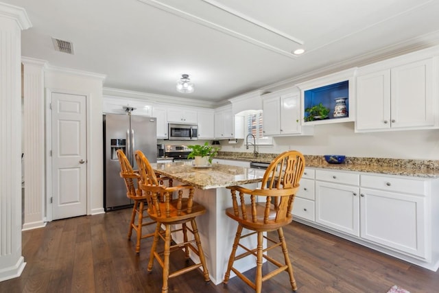 3348 Berryside Dr, Murfreesboro, TN 37128 - kitchen featuring appliances with stainless steel finishes, white cabinetry, a kitchen breakfast bar, crown molding, and a kitchen island