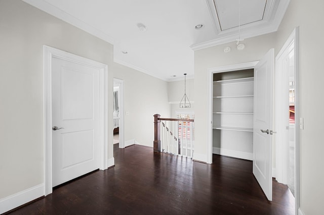 empty room featuring attic access, wood finished floors, ornamental molding, baseboards, and built in features