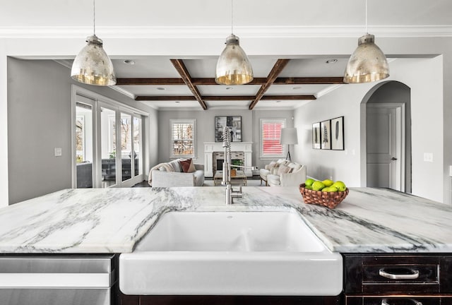 kitchen featuring open floor plan, beam ceiling, coffered ceiling, light stone counters, and a sink