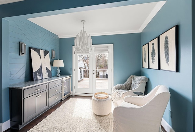 living area featuring a chandelier, ornamental molding, wine cooler, baseboards, and french doors