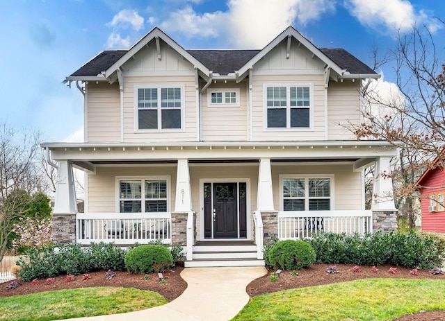 craftsman inspired home featuring covered porch, board and batten siding, stone siding, and roof with shingles
