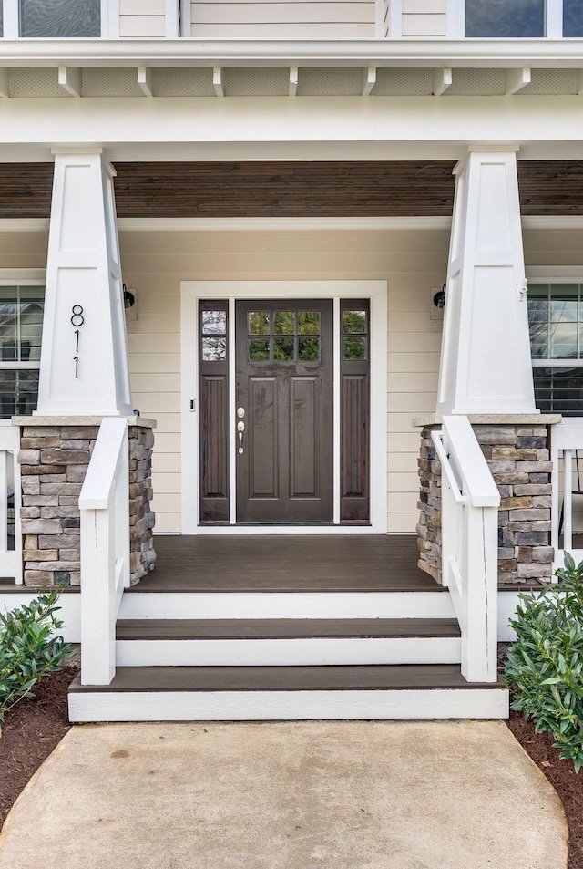 property entrance featuring covered porch and stone siding