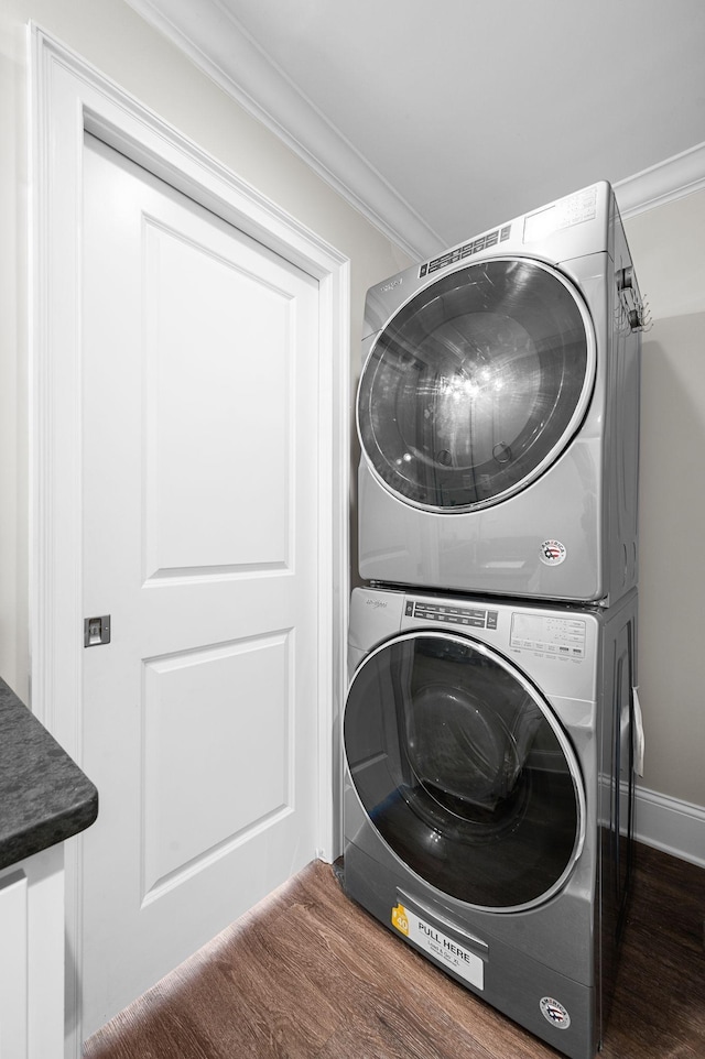 laundry room with estacked washer and dryer, crown molding, and wood finished floors