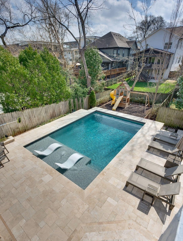 view of swimming pool featuring a playground, a patio area, and a fenced backyard