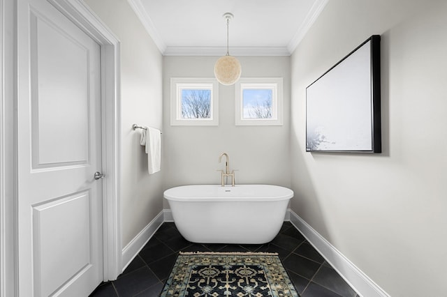 bathroom featuring baseboards, crown molding, a freestanding tub, and tile patterned floors