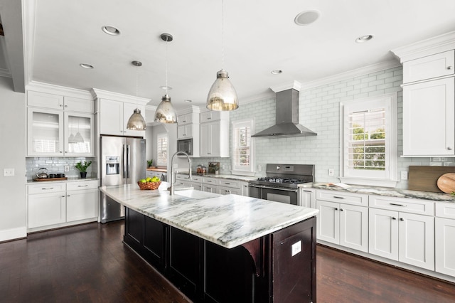 kitchen featuring stainless steel appliances, wall chimney exhaust hood, ornamental molding, backsplash, and a sink