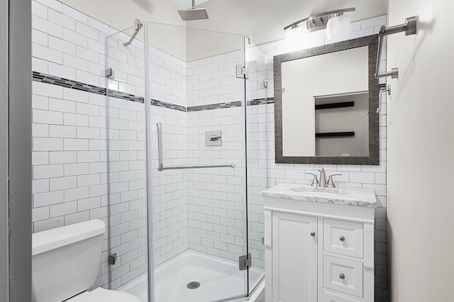 full bathroom featuring tile walls, a stall shower, vanity, and toilet
