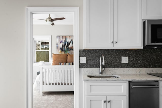 kitchen featuring a sink, stainless steel microwave, dishwasher, backsplash, and a ceiling fan