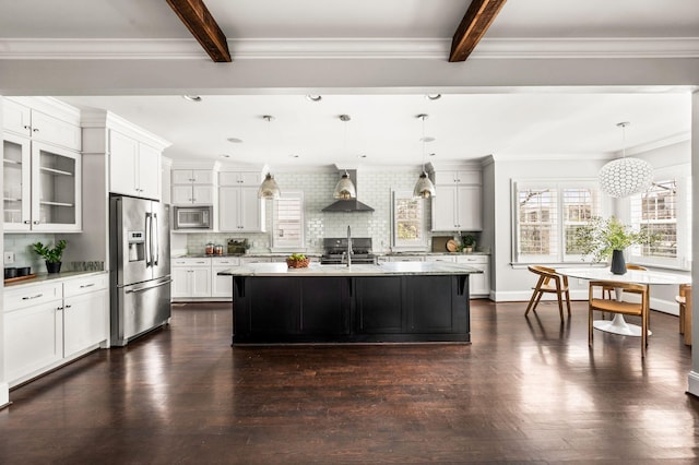 kitchen featuring stainless steel appliances, wall chimney exhaust hood, beamed ceiling, backsplash, and glass insert cabinets