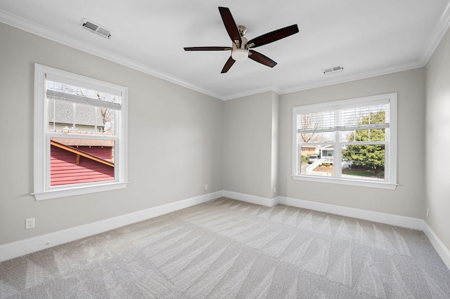 empty room featuring a ceiling fan, light colored carpet, ornamental molding, and baseboards