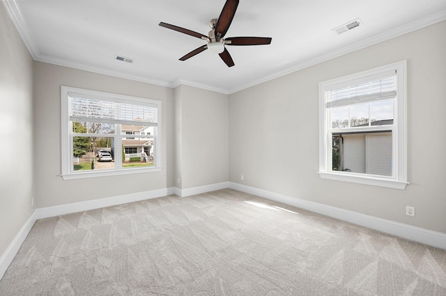 carpeted spare room with ceiling fan, plenty of natural light, ornamental molding, and baseboards