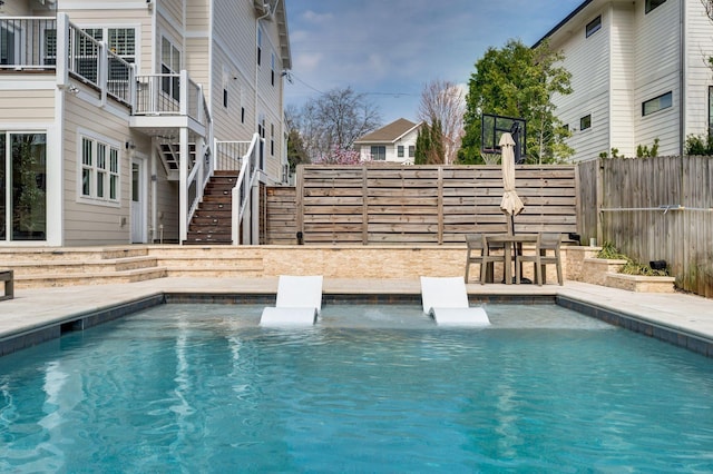 view of swimming pool with a fenced backyard and stairway