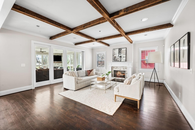 living area featuring beamed ceiling, baseboards, dark wood-style flooring, a glass covered fireplace, and coffered ceiling