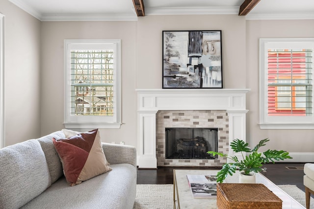 living area with wood finished floors, a fireplace, beam ceiling, and ornamental molding