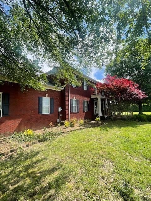 rear view of property with a lawn and brick siding