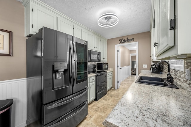 kitchen with black appliances, a sink, tasteful backsplash, light countertops, and a textured ceiling