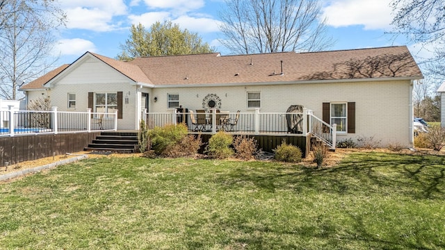 rear view of property featuring a wooden deck, brick siding, a lawn, stairs, and a shingled roof